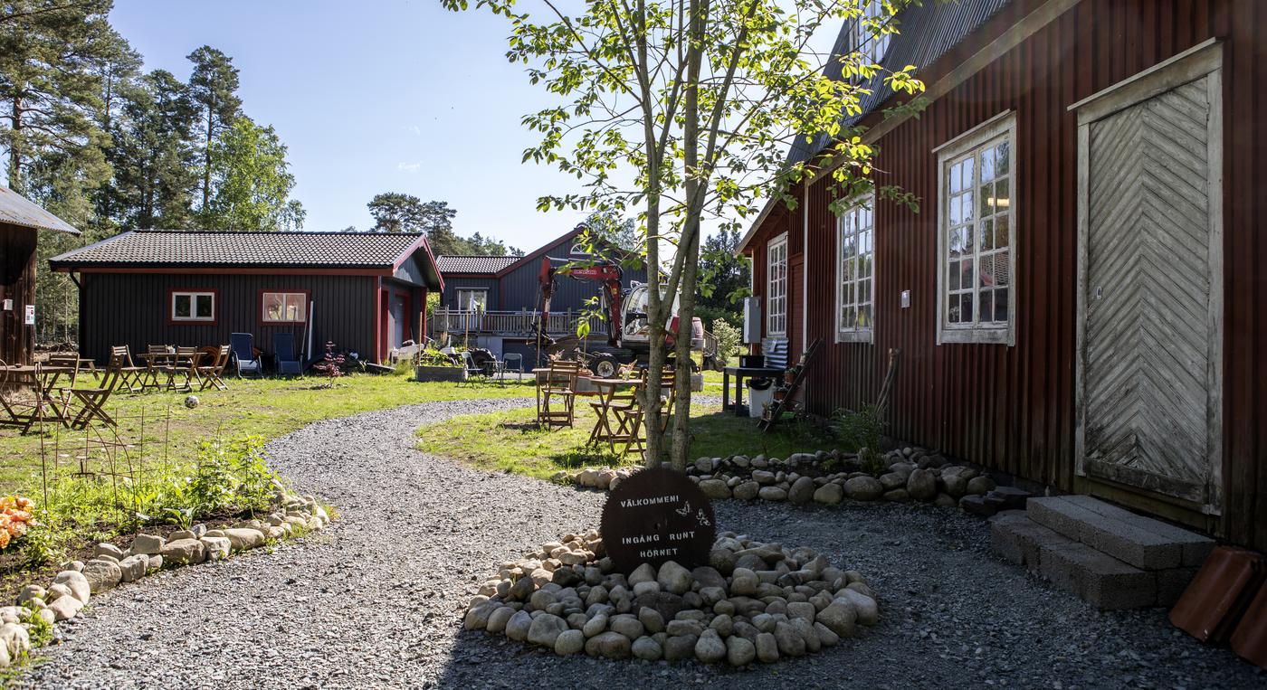 Pittoresk gård med vindlande grusgångar och cafébord utspridda i gräset.