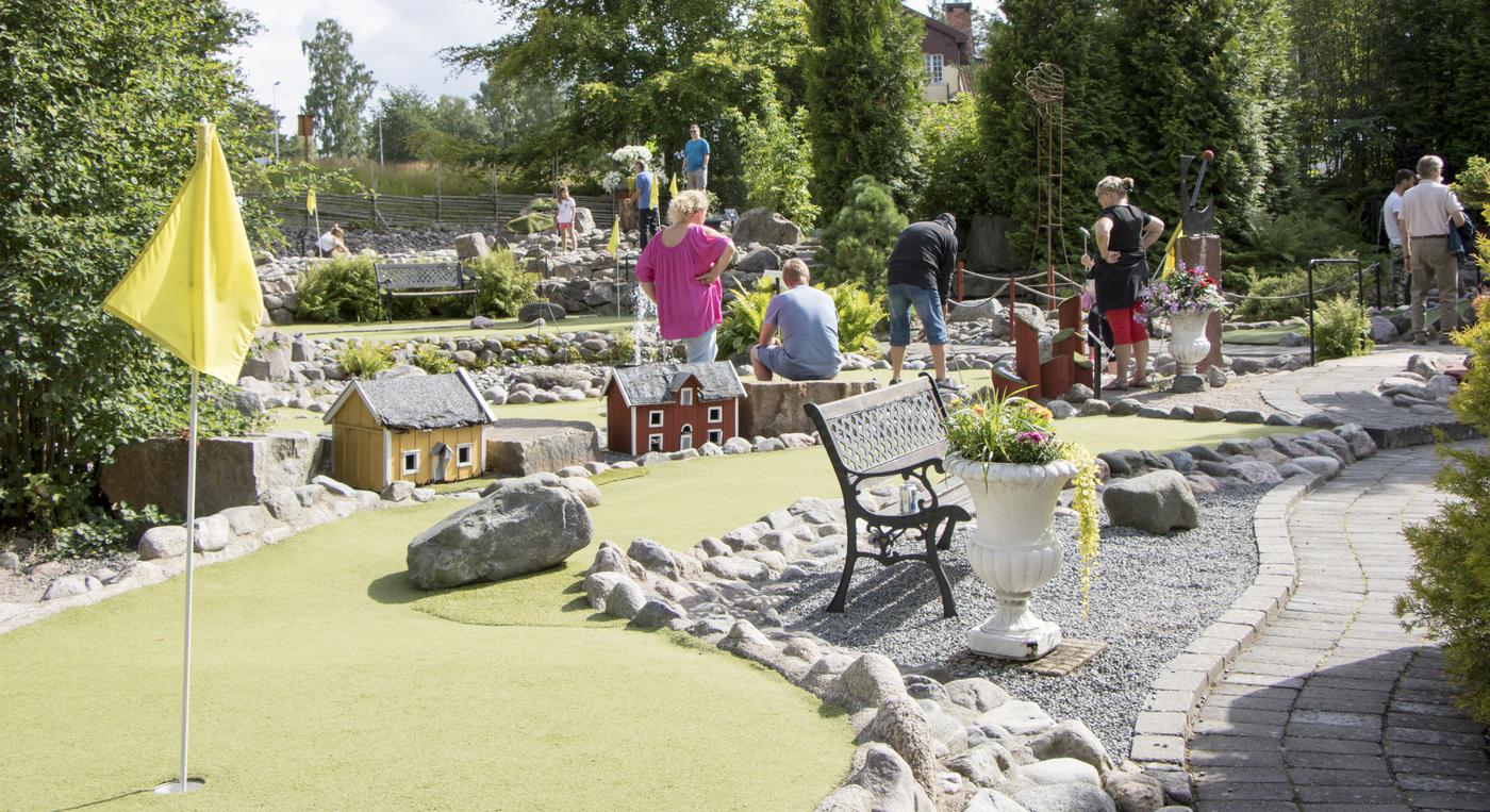 Äventyrsgolfbana med små hus och stenar som omgärdar banorna.