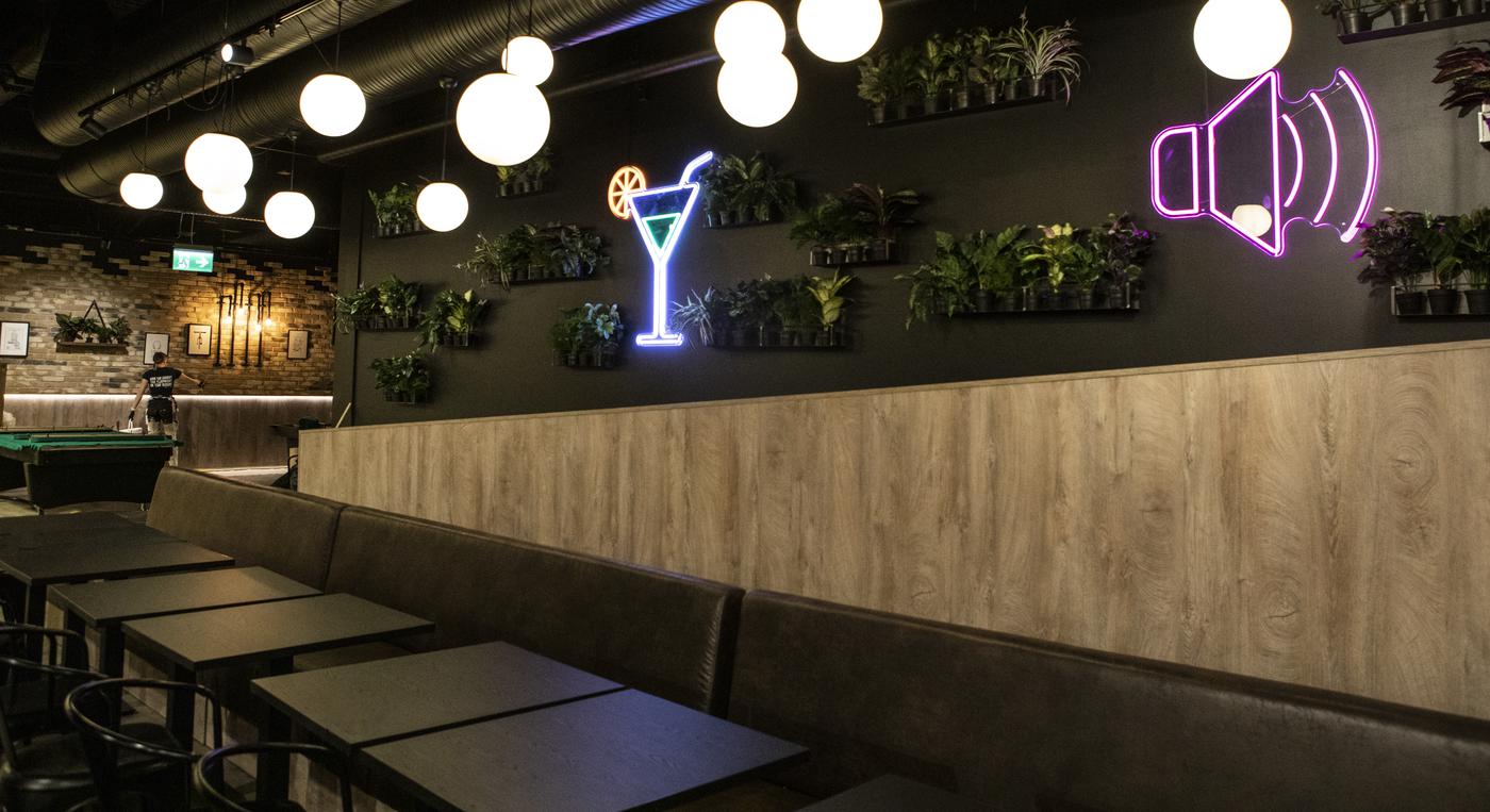 Restauranginteriör med neonskyltar och mörk inredning