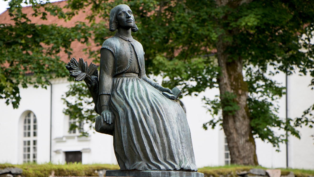 En staty av Lina Sandell framför Fröderyds kyrka.