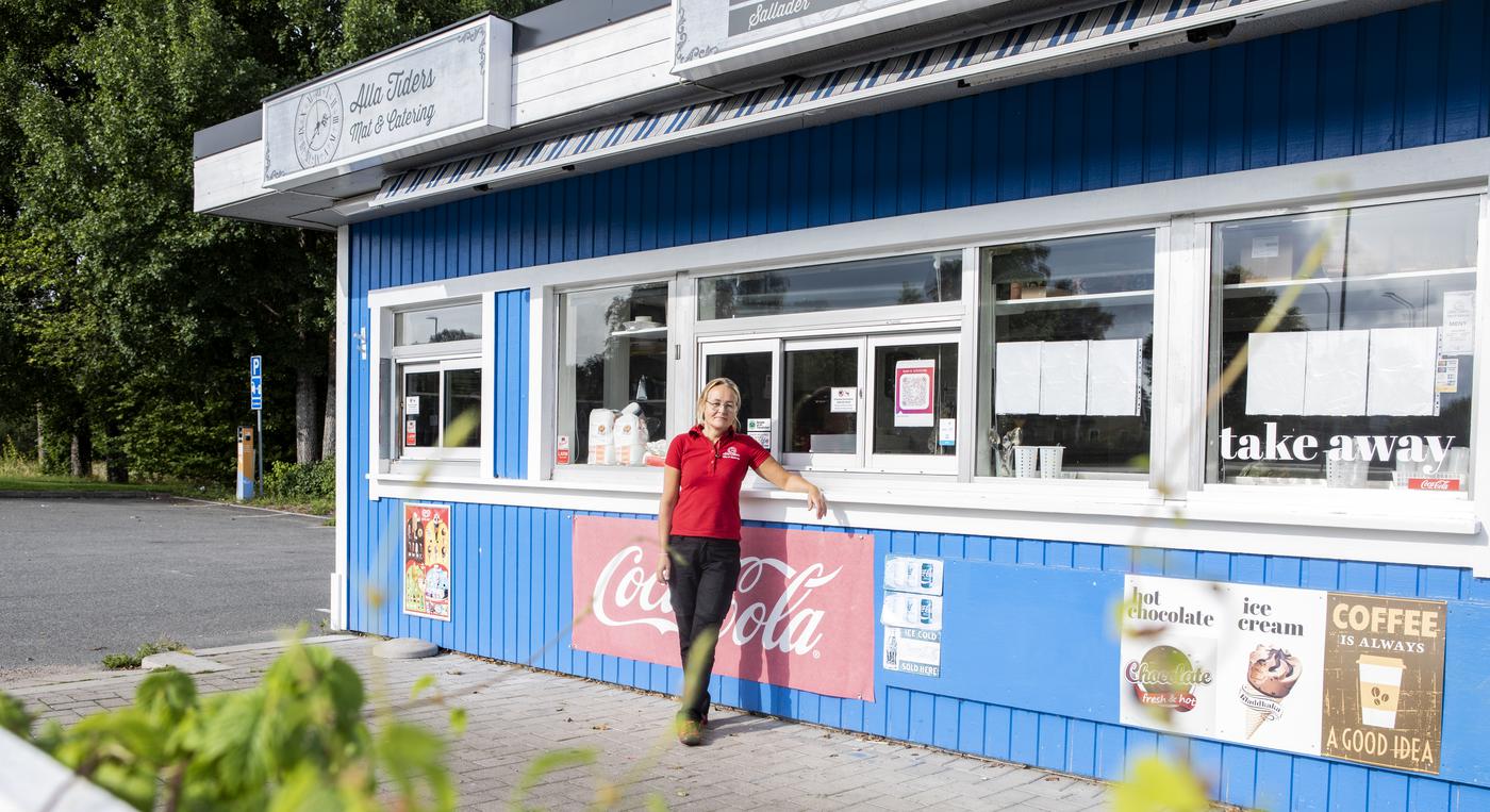 En kvinna står framför en kioskbyggnad.