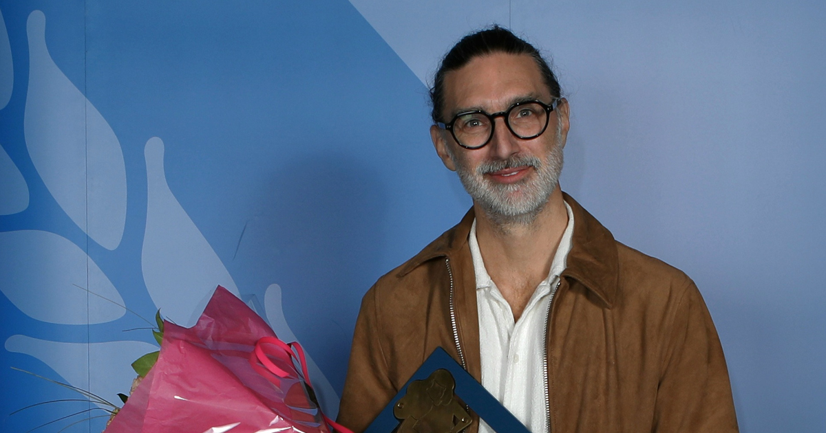 En man står framför en kuliss och håller i en blombukett.