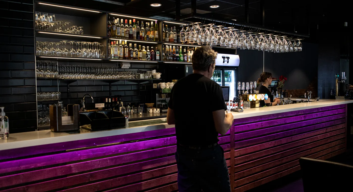 En man som står framför en lila bar och en kvinna som står bakom disken.