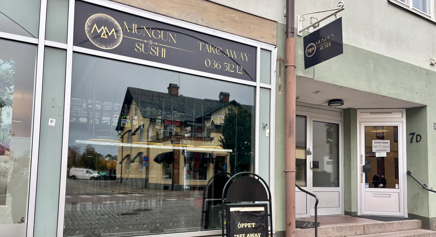 En butiksfasad med en skylt framför sig.