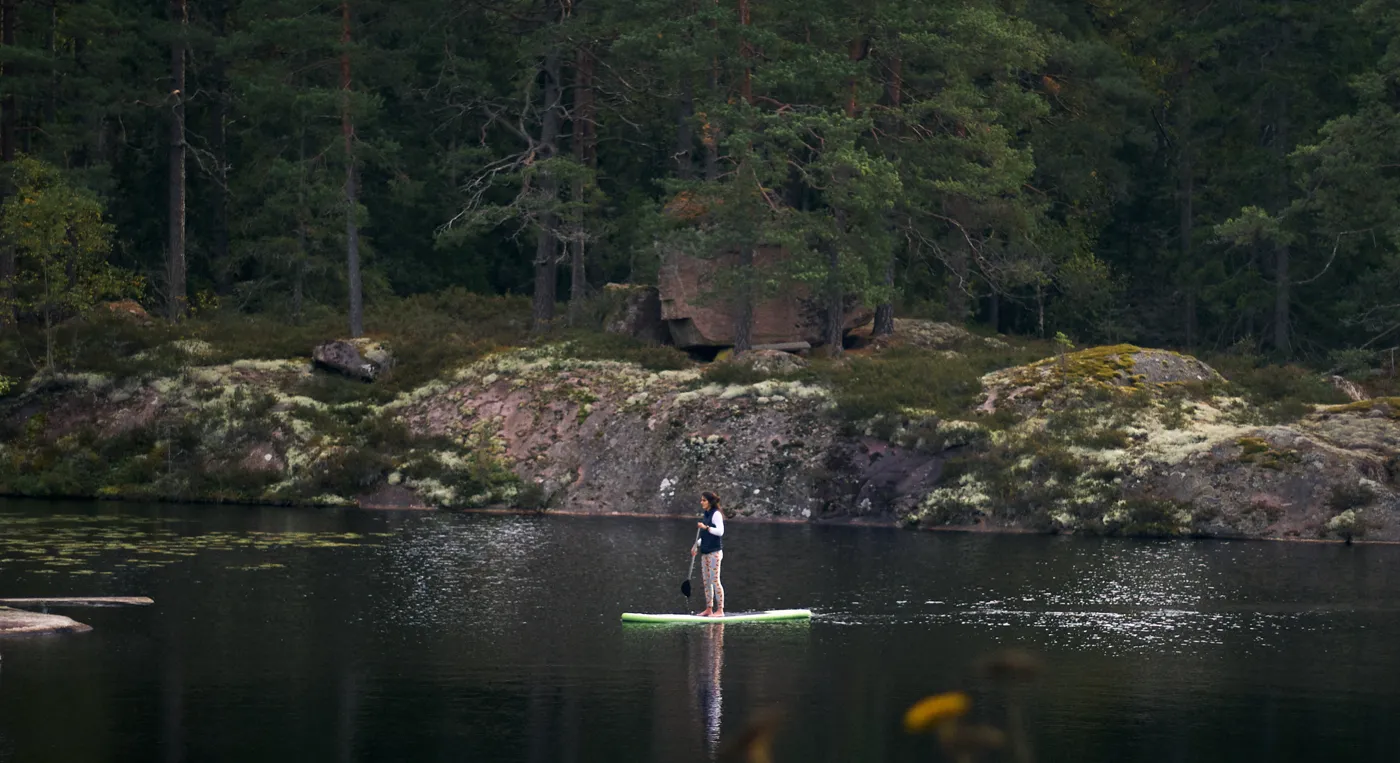 En person som står på en surfbräda i en sjö.