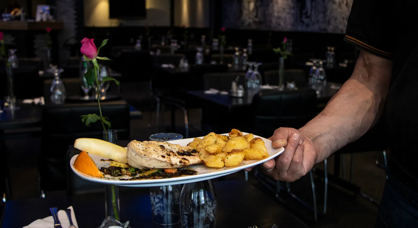 En person som håller en tallrik med mat på en restaurang.