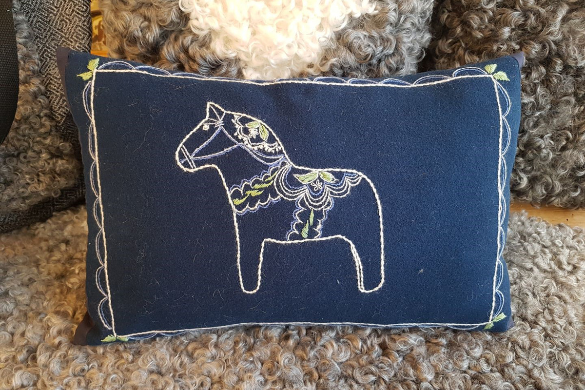 En kudde med en broderad dalahäst.