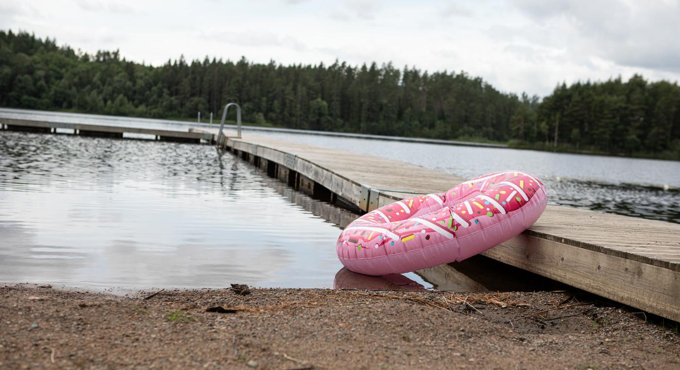 En badring som ser ut som en donut vilar mot en brygga vid en sjö