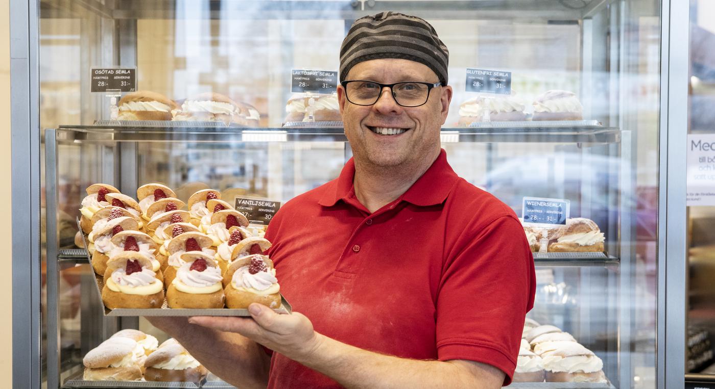 En man håller en plåt med semlor