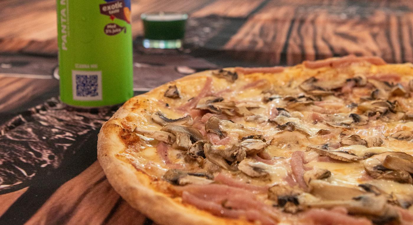 En pizza och en läskburk på ett bord