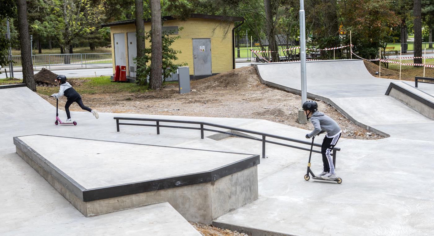 Två barn åker kickbike i en skatepark