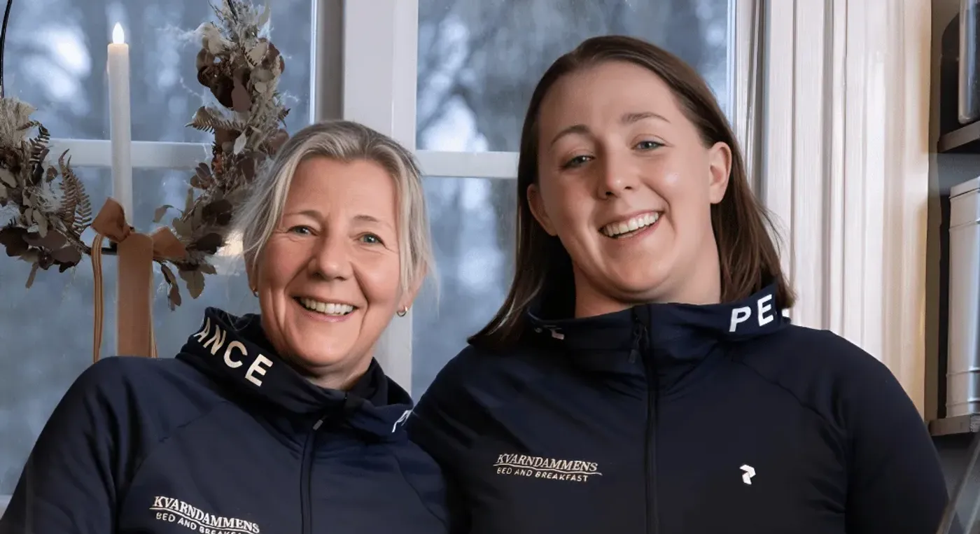 Två kvinnor som står bredvid varandra framför ett fönster.