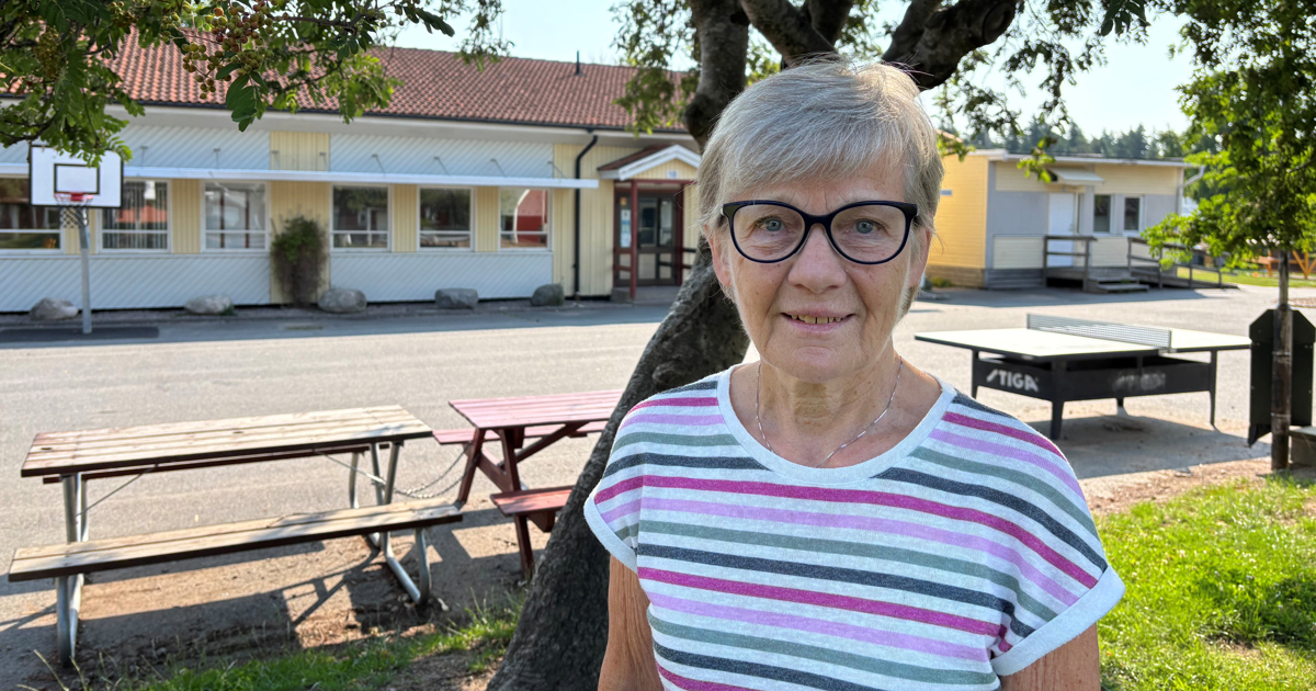 Äldre kvinna står på en tom skolgård.