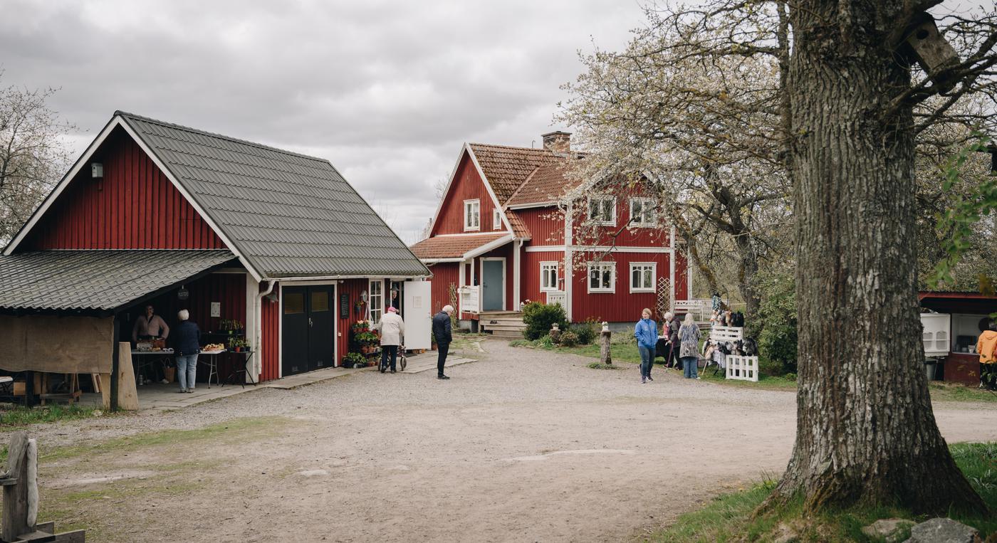 En gård med två röda byggnader och människor som rör sig