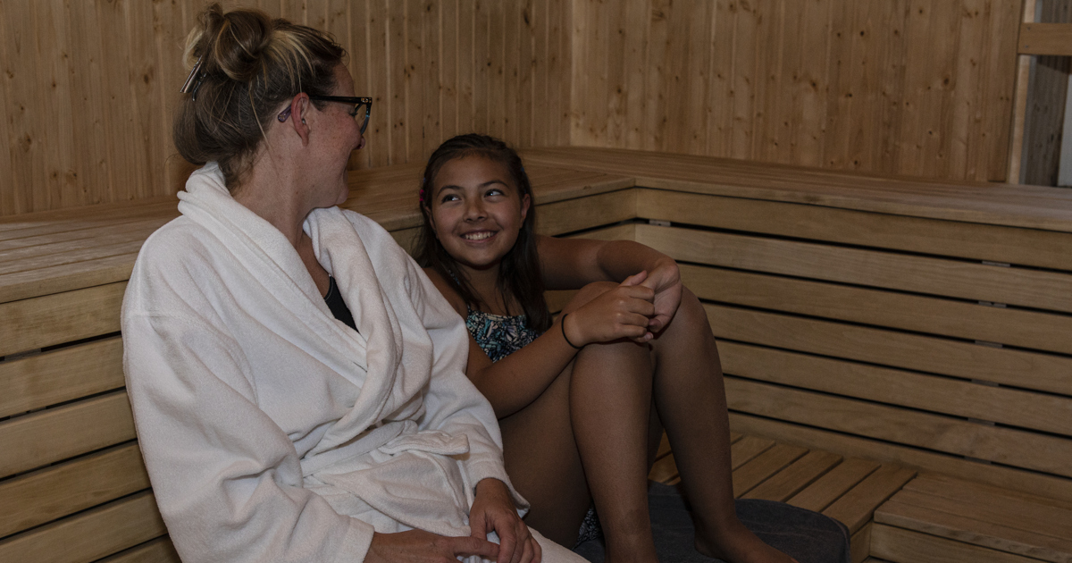 En kvinna och en flicka sitter i en bastu.